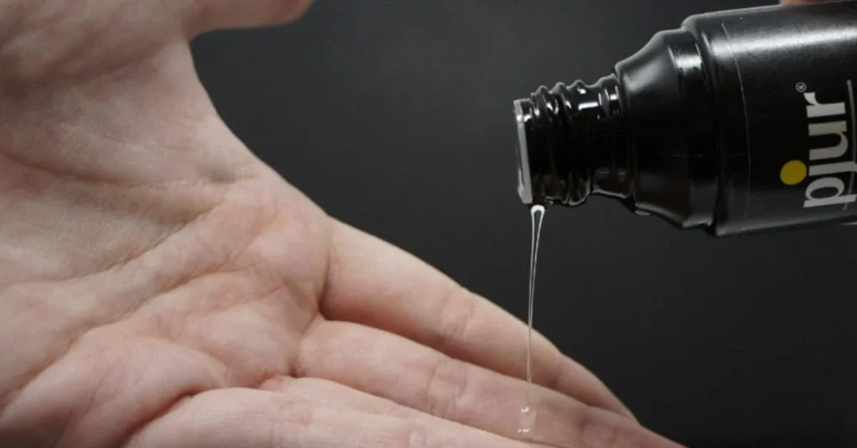 Hand with lubricant gel being poured from a black bottle for intimate use