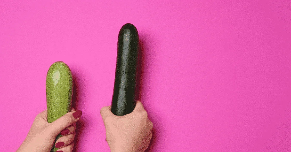 To hender holder grønne agurker mot rosa bakgrunn, symboliserer sexleketøy for par