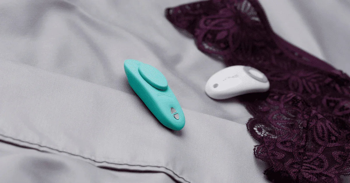 Two wearable vibrators on a bed with lace lingerie, intimate massage product setting