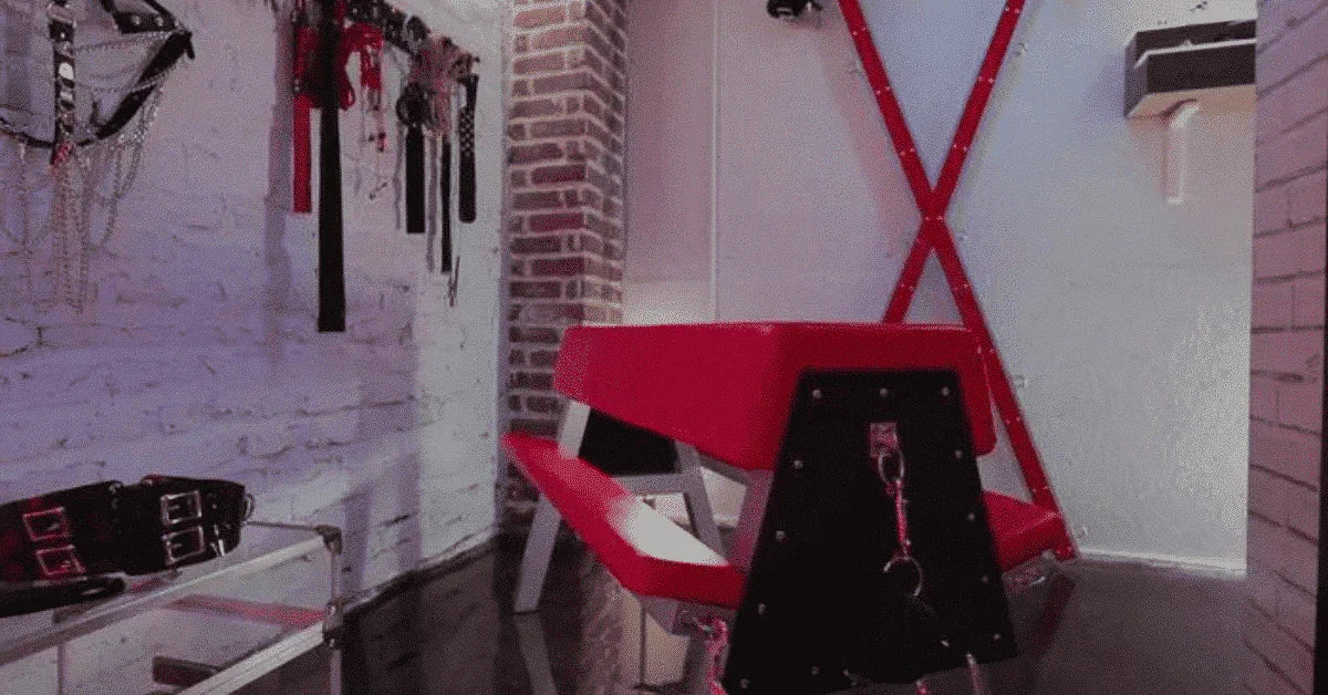 Modern red and black adult playroom with furniture, restraints, and brick accent walls