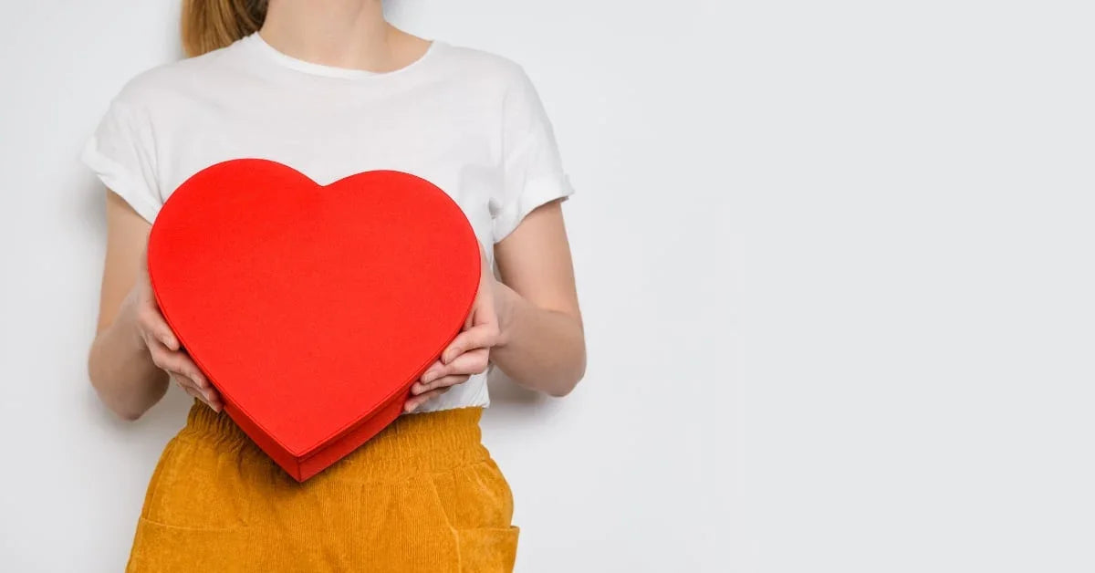 Kvinne som holder en stor rød hjerteformet eske, som symboliserer kjærlighet og Valentinsdagen.