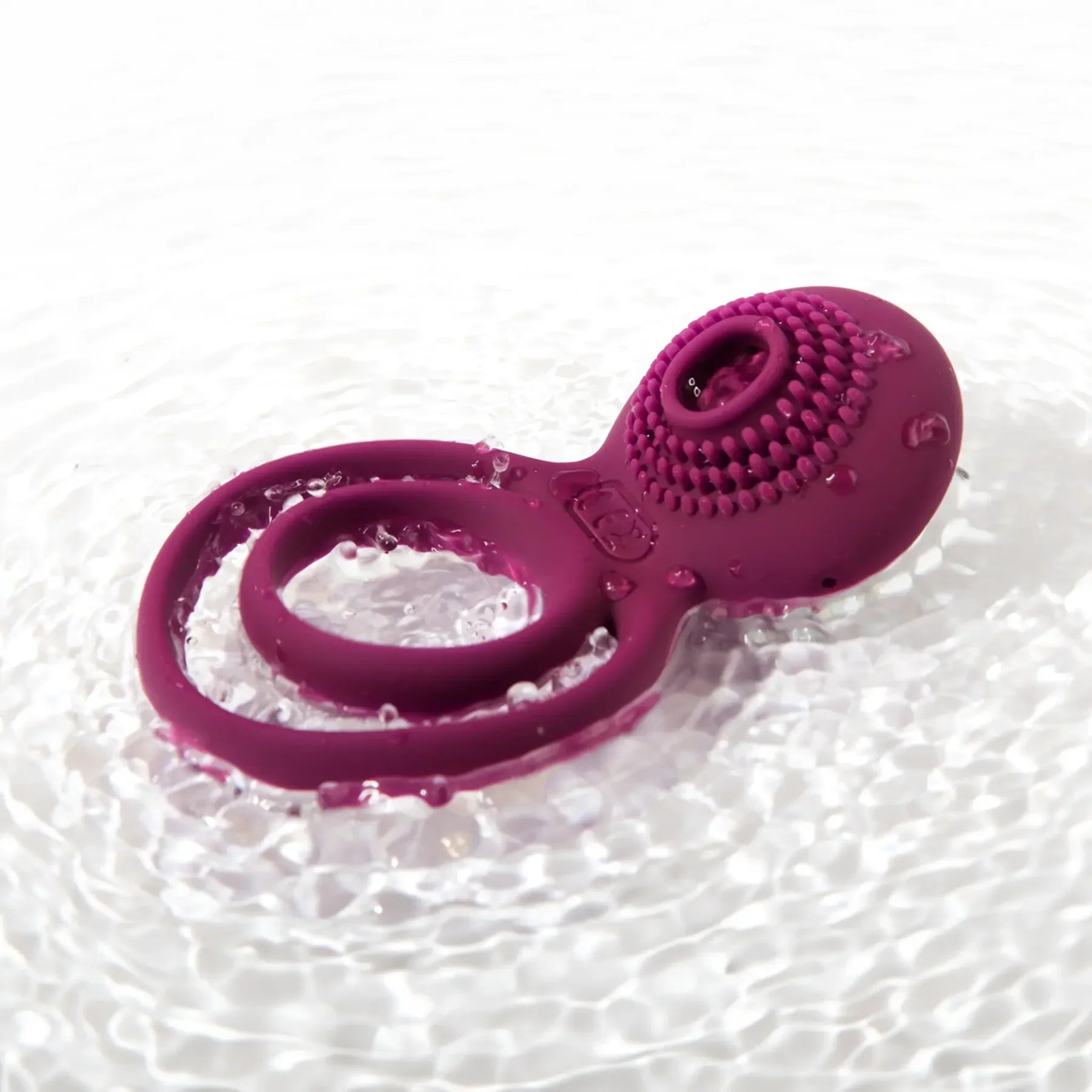 Purple silicone vibrating ring with textured surface, waterproof, on rippling water