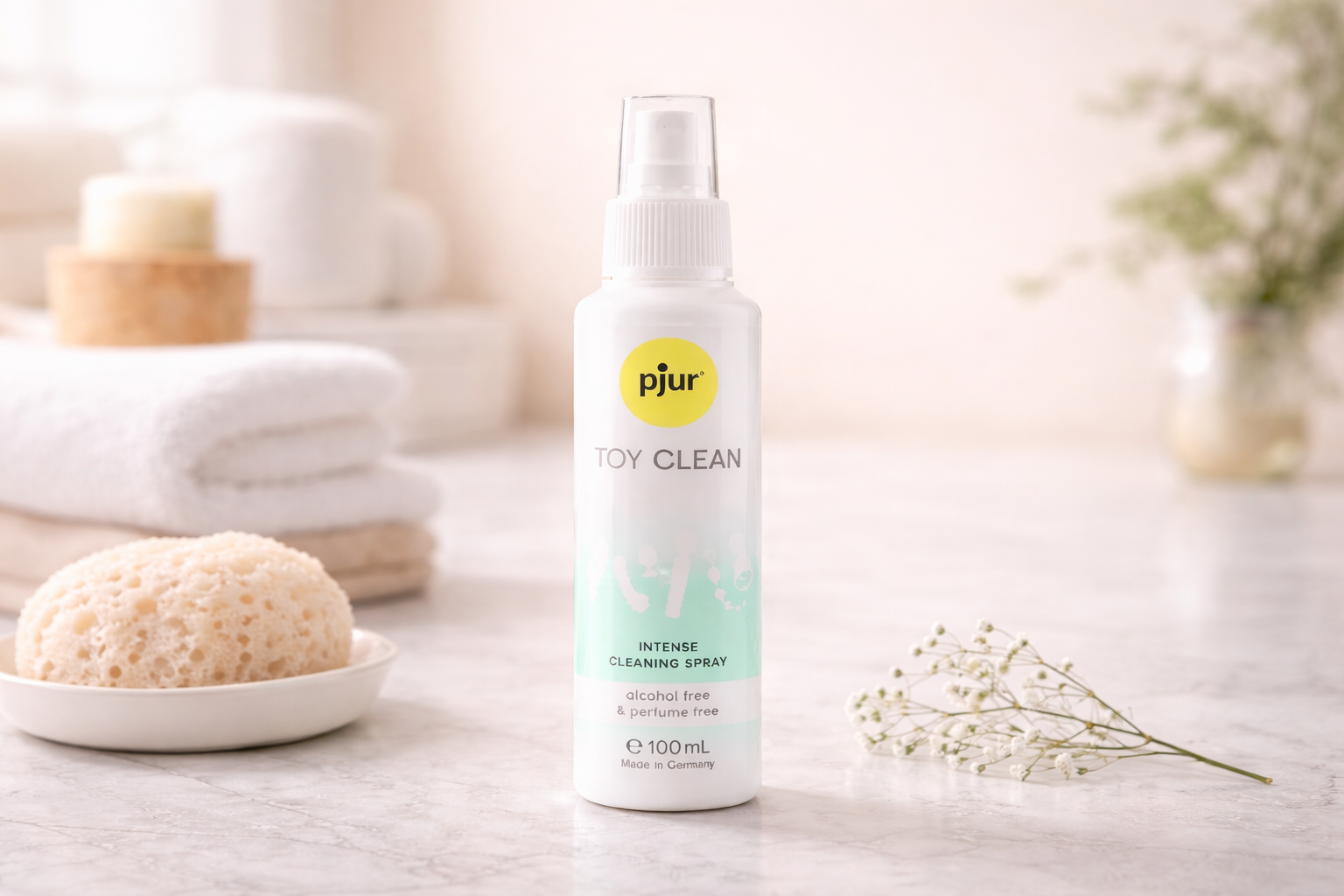 Pjur toy cleaning spray bottle on bathroom counter with soft towels and sponge