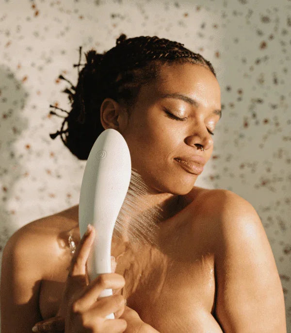 Woman enjoying a waterproof personal massager on her shoulder in a shower setting
