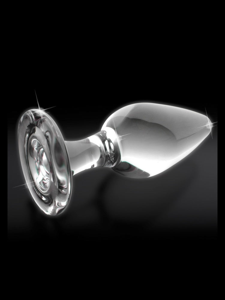 Pipedream Icicles No 26 Buttplug Klar – nærbilde av glaspluggen liggende horisontalt med funkelnde refleksjoner mot mørk bakgrunn