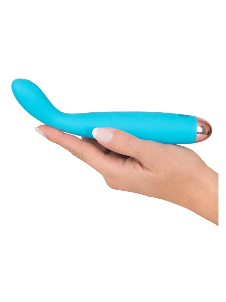 Hånd som holder en turkis G-punktvibrator liggende i håndflaten, sett fra siden