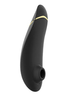 Womanizer Premium 2 klitorisstimulator sett fra siden, med stimulatorhodet vendt fremover. Matt svart silikon med gullfarget detalj og rund åpning.