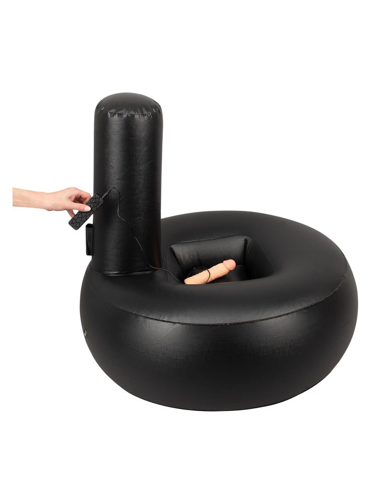 Oppblåsbar sexpute med realistisk vibrator. Hånd holder trådbasert kontroller, med puten og vibrator synlig i bakgrunnen.