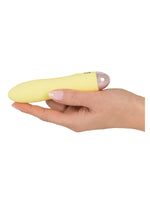 Cuties gul minivibrator liggandes i en hand, visar produktens kompakta storlek med roséguldsfärgad botten och You2Toys-logotyp synlig.