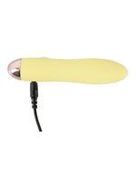 Cuties gul minivibrator liggandes på sidan med USB-laddningskabel ansluten till porten i botten mot vit bakgrund.