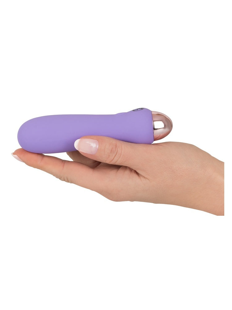 Hånd holder Cuties minivibrator i lilla liggende i håndflaten, viser den kompakte størrelsen.