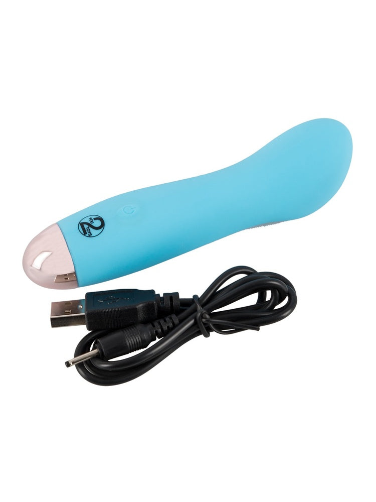 Cuties blå minivibrator med medfølgende svart USB-ladekabel liggende ved siden av hverandre mot hvit bakgrunn.