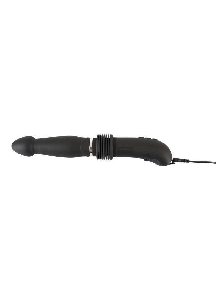 RC Fucking Machine liggende horisontalt med USB-ladekabel koblet til håndtaket mot hvit bakgrunn.