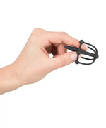 Hand holding small black silicone chastity cage, intimate adult product for couples