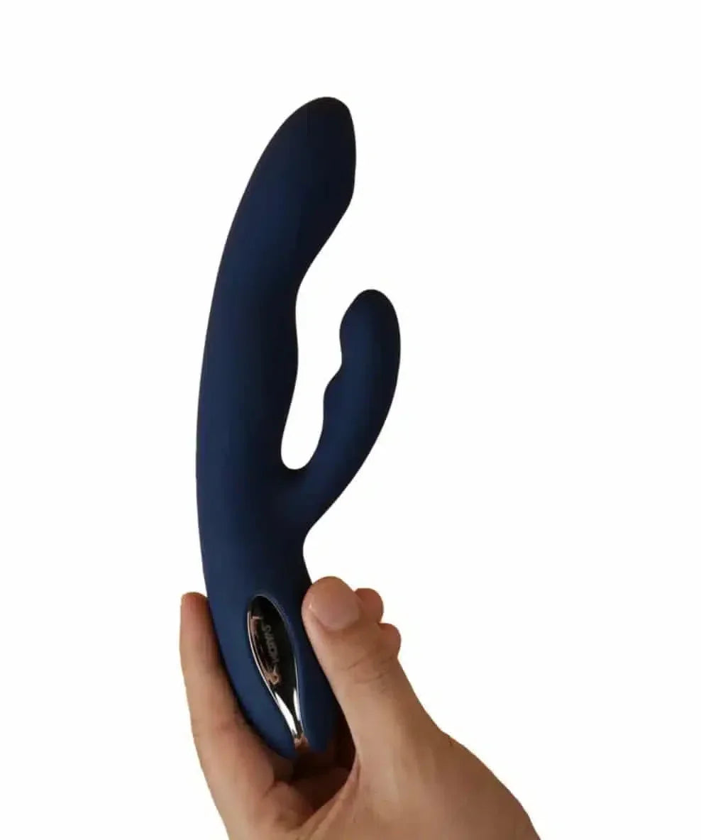 Hand holding a blue silicone dual-motor rabbit vibrator against white background