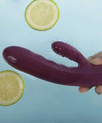 Purple waterproof dual-action vibrator held over water with floating lemon slices