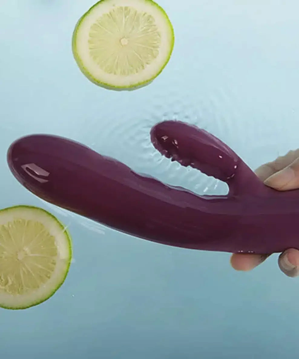 Purple waterproof dual-action vibrator held over water with floating lemon slices