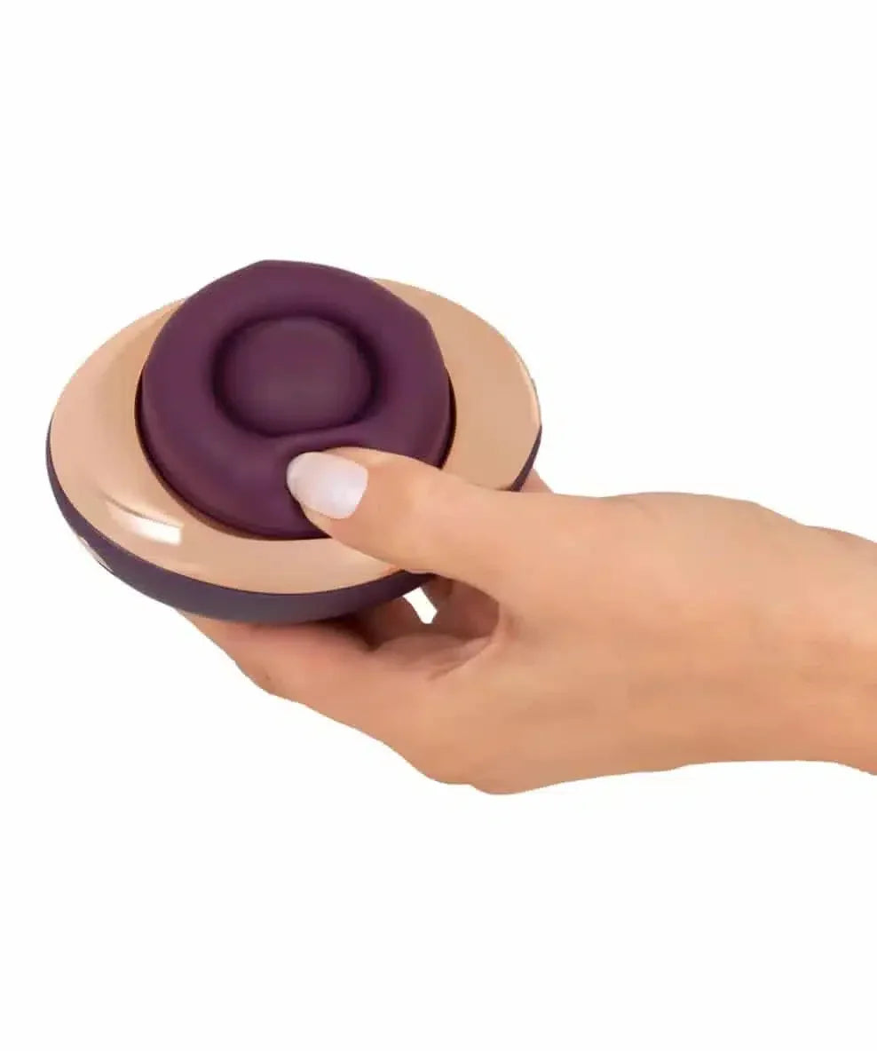 Hand holding a purple and beige personal massager with ergonomic design