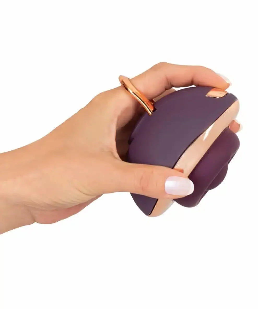 Hand holding a purple and rose gold ergonomic personal massager against white background