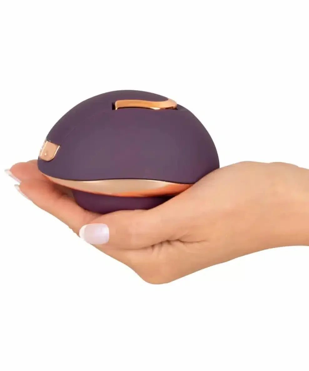 Purple and gold ergonomic massager held in a hand on white background