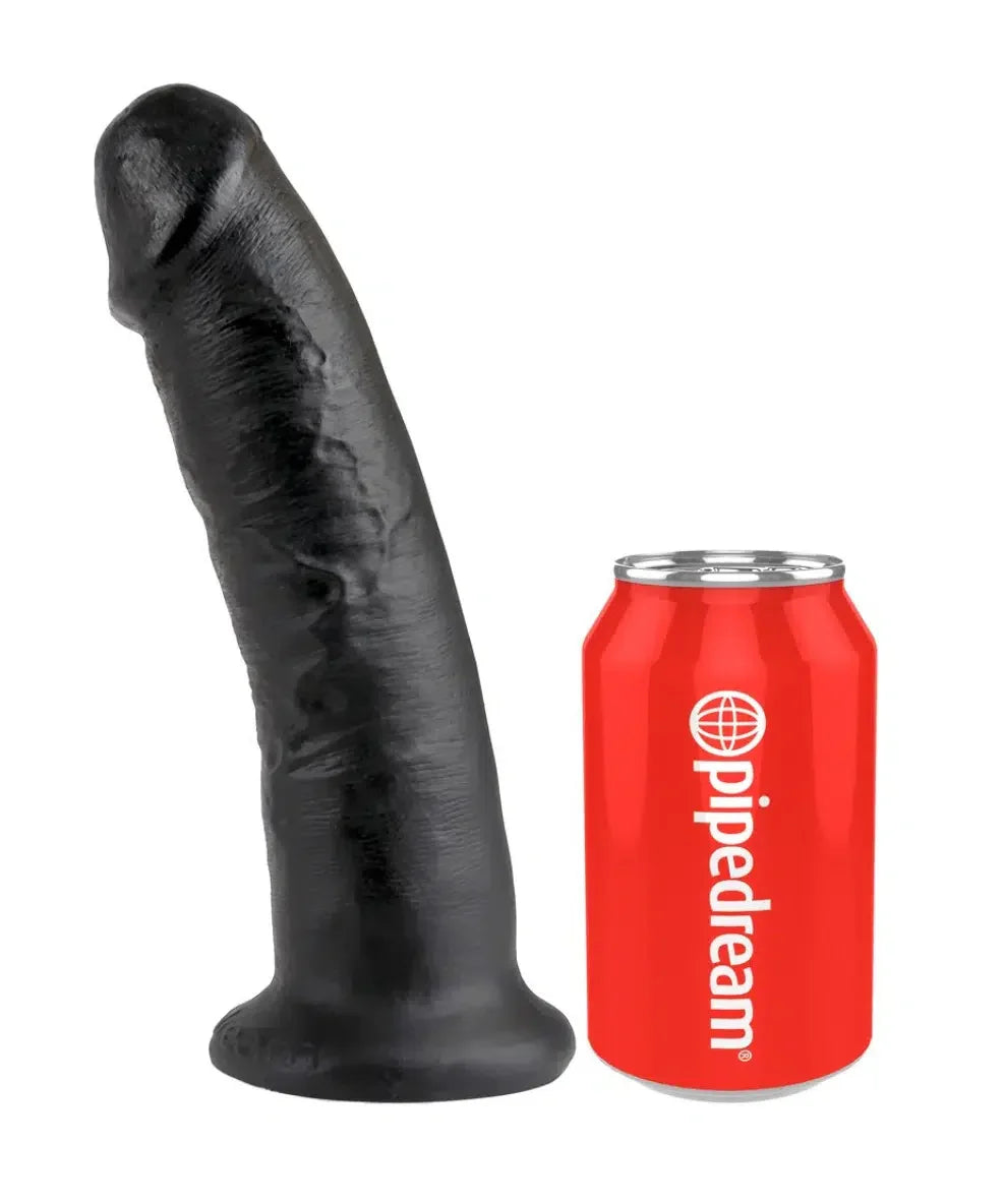 Black realistic dildo standing beside a red Pipedream can for size comparison on white background