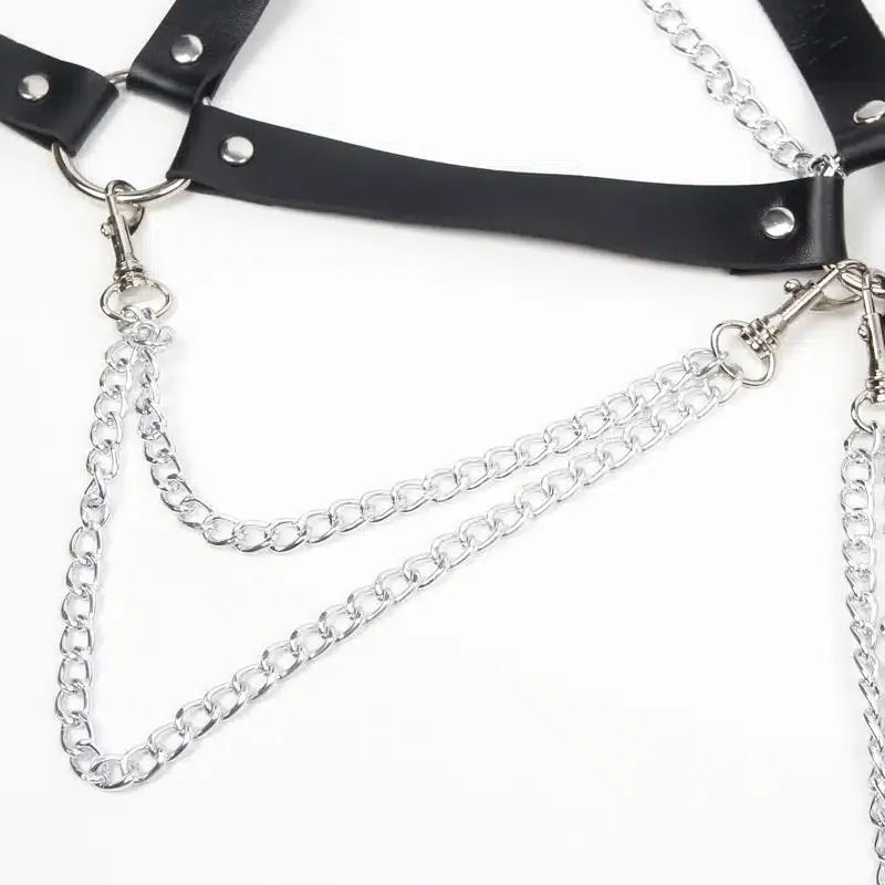 Black faux leather harness with silver metal chains and O-rings on white background