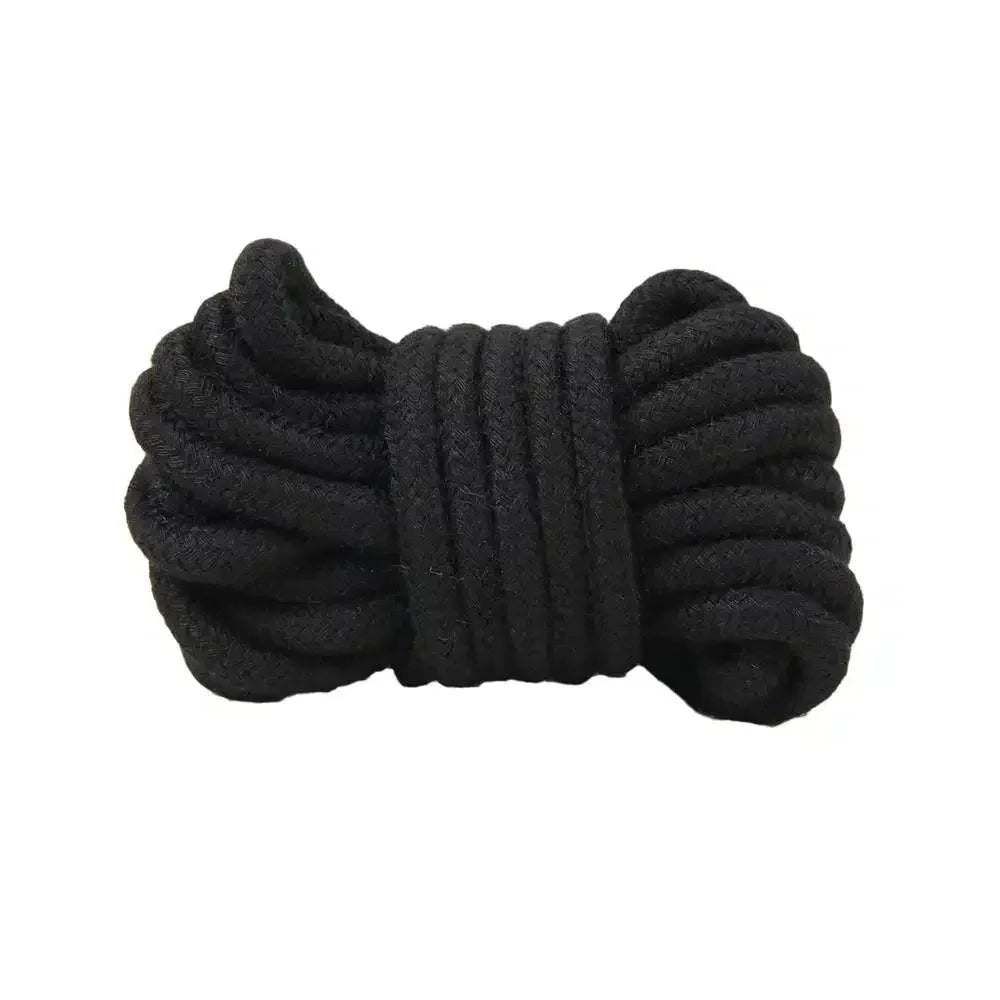 Coiled black bondage rope on white background, soft cotton restraint accessory.