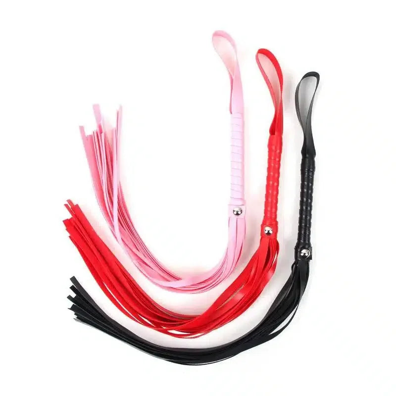 Three faux leather floggers in pink, red, and black with looped handles on white background
