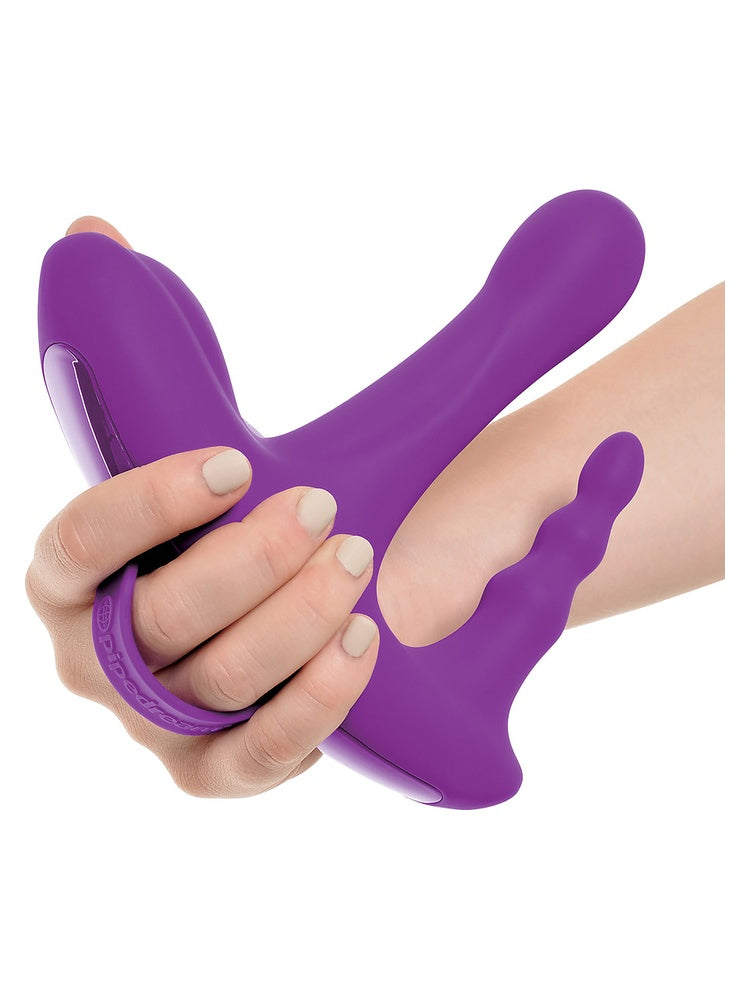 Hånd som holder 3Some Rock N' Ride vibrator med posisjoneringsrem rundt håndleddet, viser alle tre armer