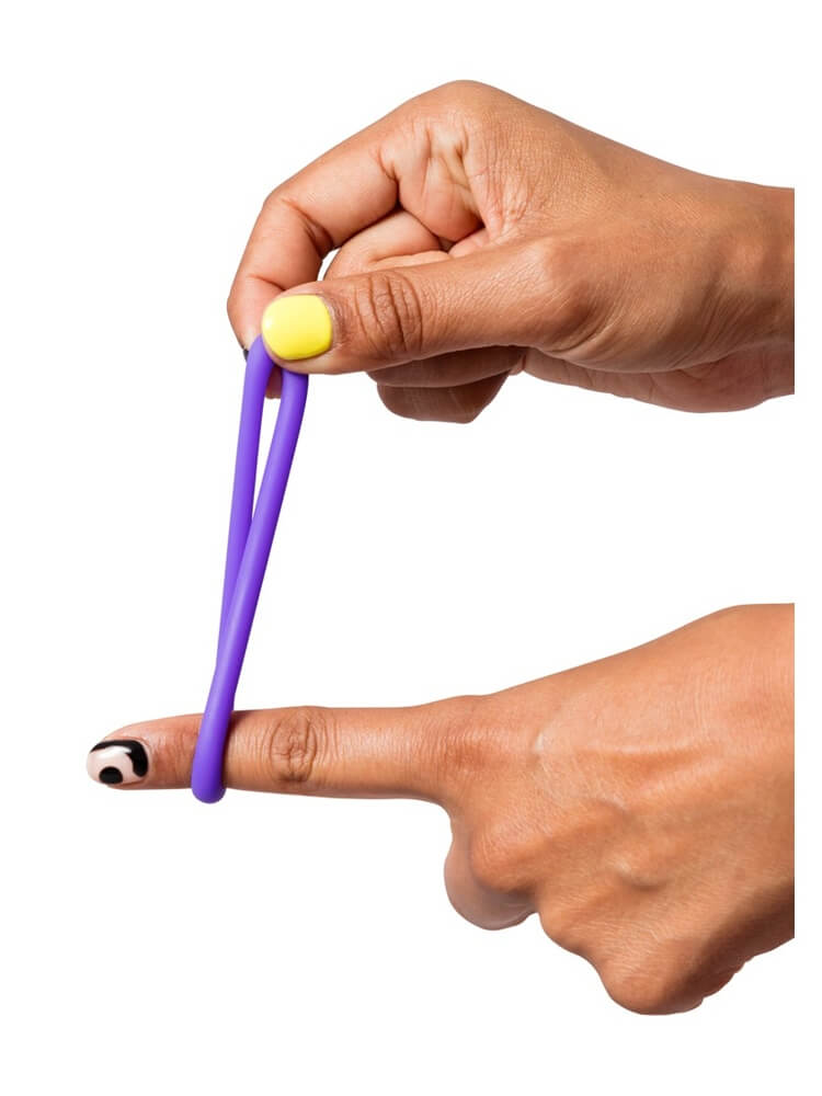 Elastisk lilla penisring som strekkes mellom fingre