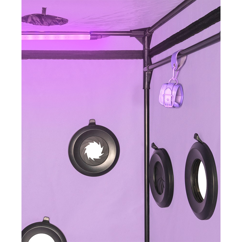 Innendørs telt med lilla belysning, ventilasjonsåpninger og et par håndjern hengt på stang.