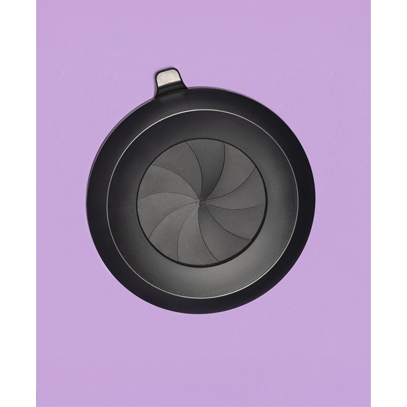 Svart rund sexleketøy-lokk med spiraldesign på lilla bakgrunn