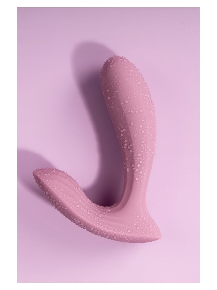 Svakom Erica trusevibrator med vannperler på overflaten, liggende på rosa bakgrunn, viser vanntetthet
