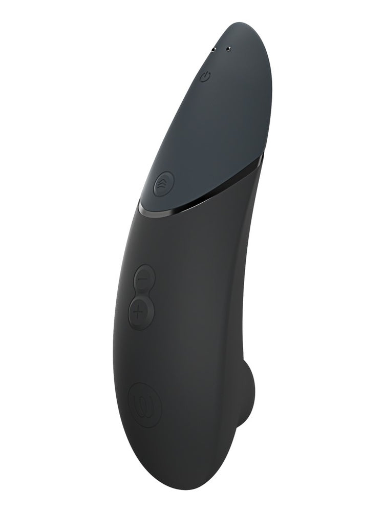 Womanizer Next sort sett fra kontrollsiden, med av/på-knapp, Climax Control, −/+ knapper, logo og magnetiske ladekontakter.