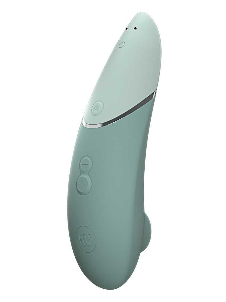 Womanizer Next sett fra kontrollsiden, med av/på-knapp, Climax Control, −/+ knapper, logo og magnetiske ladekontakter.