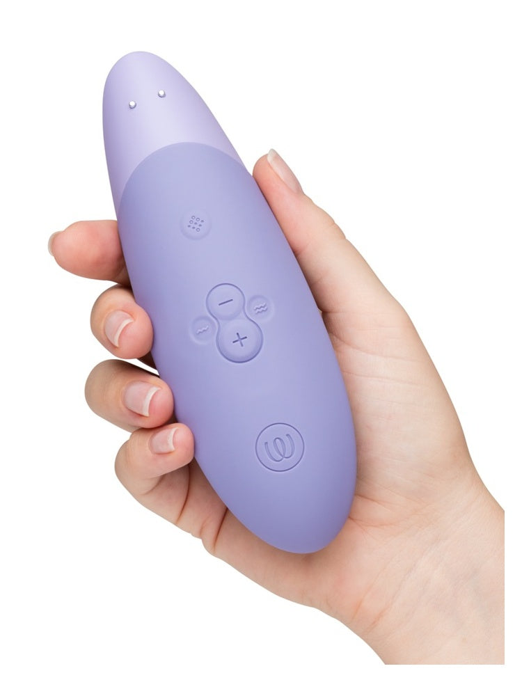 Hånd som holder Womanizer Enhance bakfra, med knapper og logo.