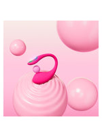 Lovense Lush 4 stående på en rosa, bølgete overflate med dekorative kuler, og LED-lys aktivt på kontrollenheten.