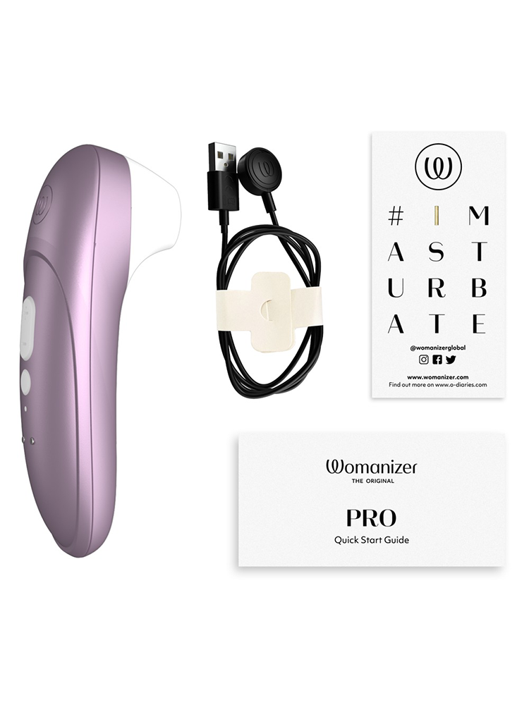 Lilla Womanizer stimulator med lader, brukerveiledning og instruksjonskort på hvit bakgrunn.