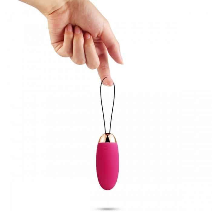 Hand holding a pink wireless bullet vibrator with loop against white background