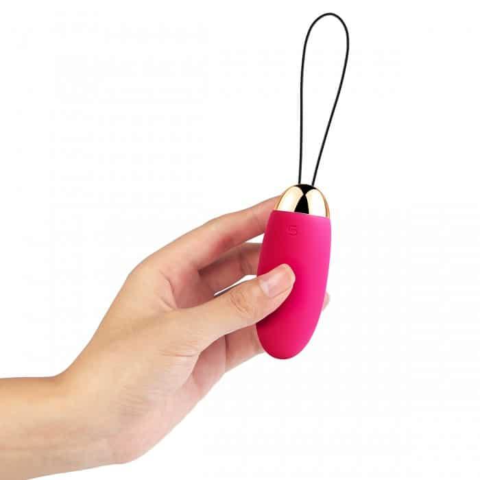 Hand holding a pink and gold wireless bullet vibrator with a looped string.