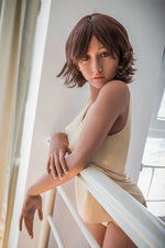 Realistic silicone love doll with short brown hair and beige lingerie leaning on railing