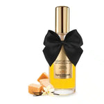 Warming massage oil bottle with gold cap, black bow, caramel pieces and vanilla flower