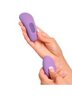 Oval lilla fjernkontroll til trusevibrator med av/på-knapp og modusknapp, vist på hvit bakgrunn.