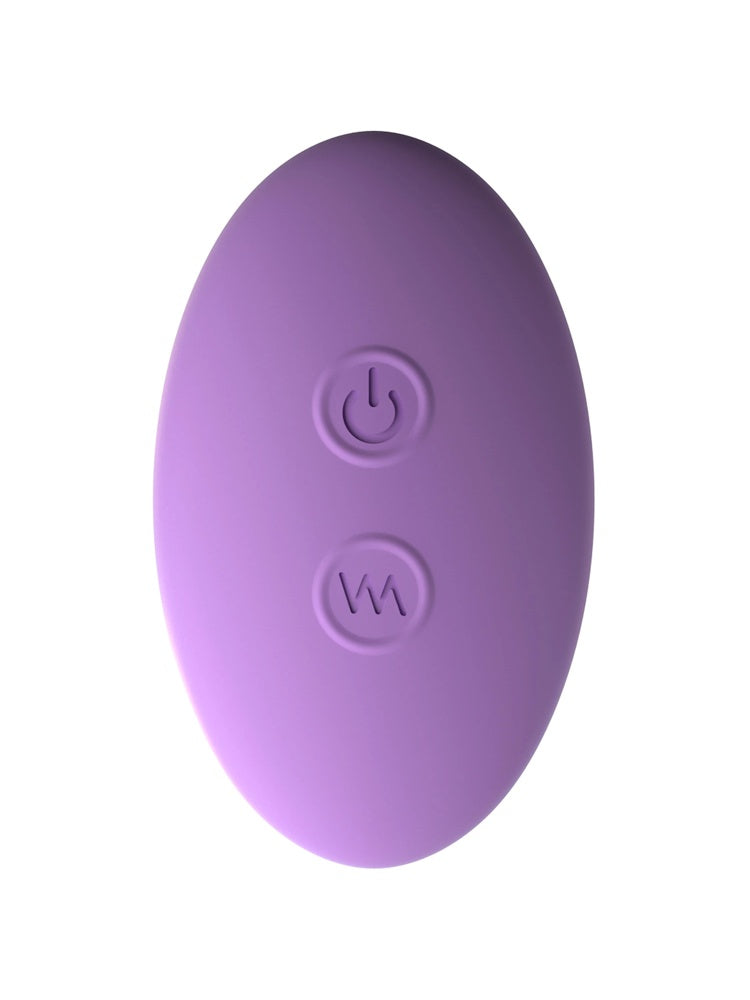 Hånd holder lilla fjernstyrt trusevibrator og oval fjernkontroll med to knapper, viser størrelse og trådløs styring.