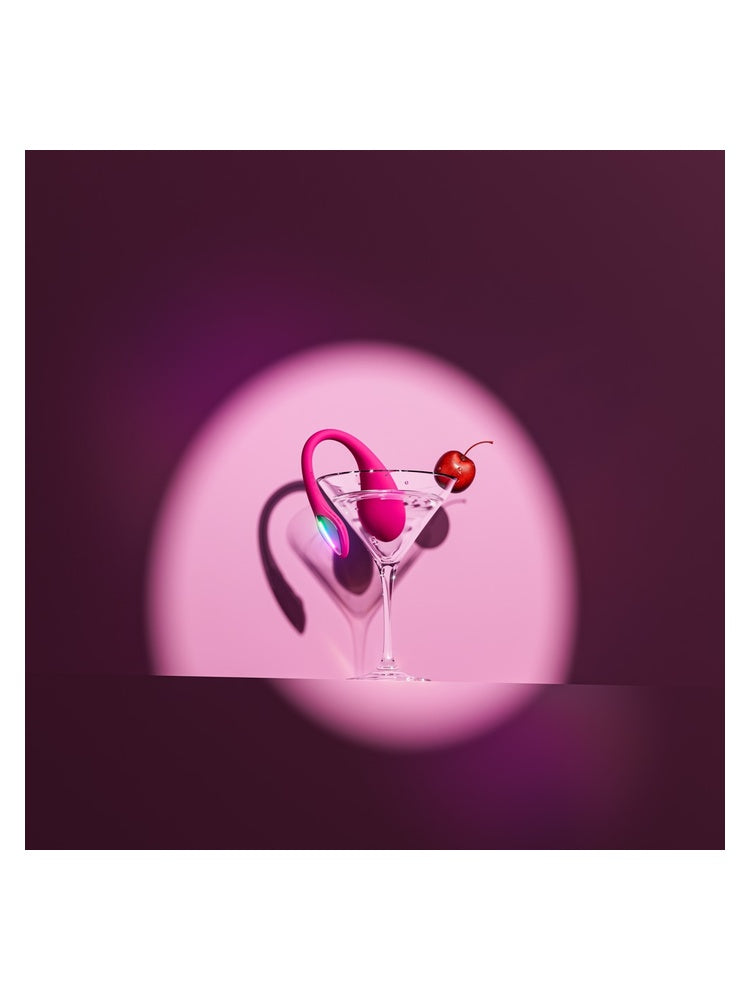 Lovense Lush Mini vibrator i martiniglass med kirsebær, mot rosa bakgrunn