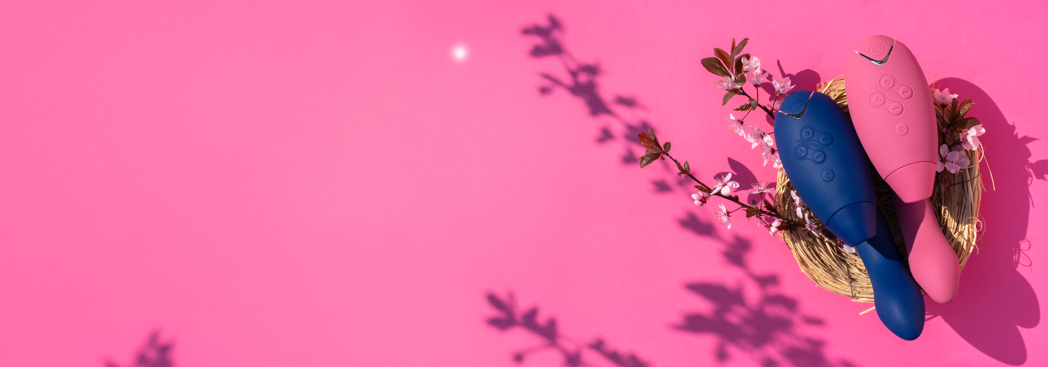 Erotiske sexleketøy i rosa og blå farger plassert i en påskekurv med blomster på rosa bakgrunn